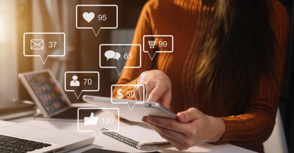 Persona utilizando una tablet con iconos de interacción digital, representando la gestión de redes sociales para empresas.